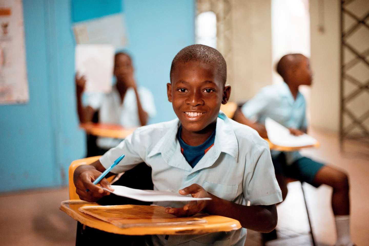 student at desk holding paper and smiling